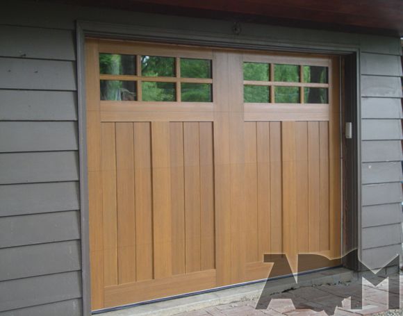 two wooden garage doors on the side of a house