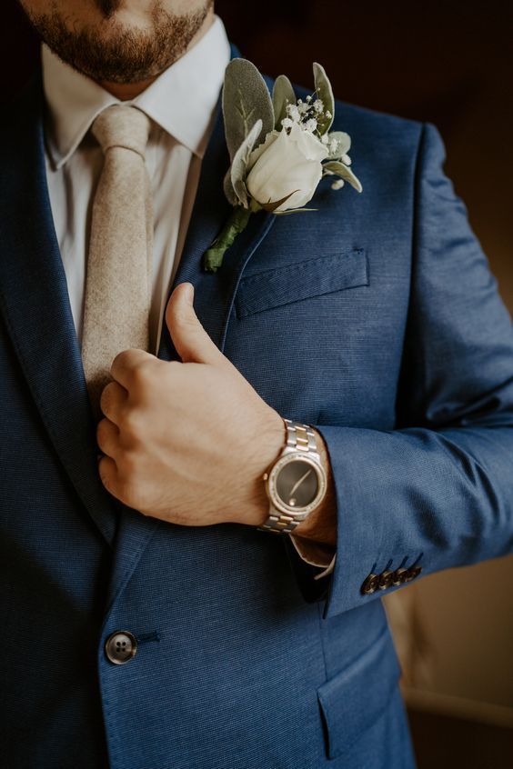 a man in a blue suit with a boutonniere and flower on his lapel