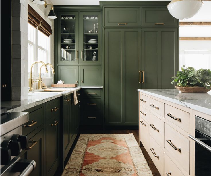 a kitchen with green cabinets and marble counter tops, along with an area rug on the floor