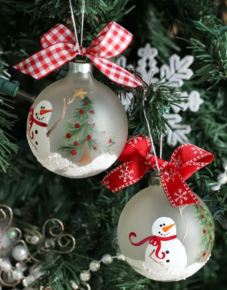 three ornaments hanging from a christmas tree decorated with red and white bows, snowman ornament