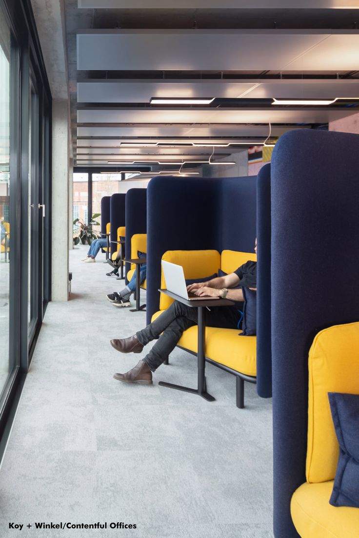 a man sitting on a yellow and blue couch in an office