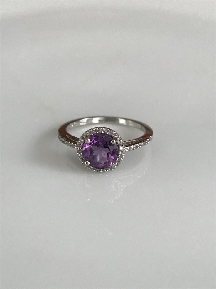 "This lovely halo ring features one round amethyst surrounded by tiny round diamonds that extend to about 1/4\" along the band on either side. The delicate purple shine of the amethyst and the twinkle of the diamonds make this ring simply dreamy! It is marked 14K, is a size 6 1/2 and is in beautiful condition. Please see all photos for details. Thank you for looking! I'm happy to offer layaway on certain items. Please ask for details." Classic Amethyst Diamond Ring With Halo Setting, Classic Purple Diamond Ring With Halo Setting, Fine Jewelry Diamond Amethyst Ring With Halo Setting, Elegant Lavender Rings With Halo Setting, Classic Amethyst Ring With Halo Setting, Classic Amethyst Halo Ring, Purple Diamond Ring With Halo Setting And Round Cut, Purple Diamond Birthstone Ring With Round Cut, Amethyst Ring With Diamond Accents, Round Cut