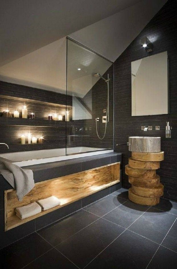 a modern bathroom with black tile and wooden accents, candles on the wall above the bathtub