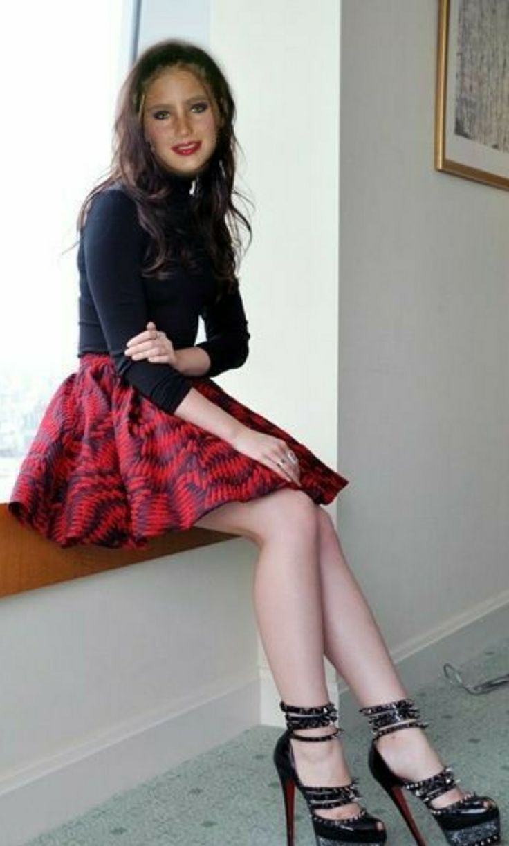 a woman is sitting on a window sill wearing high heels and a black top