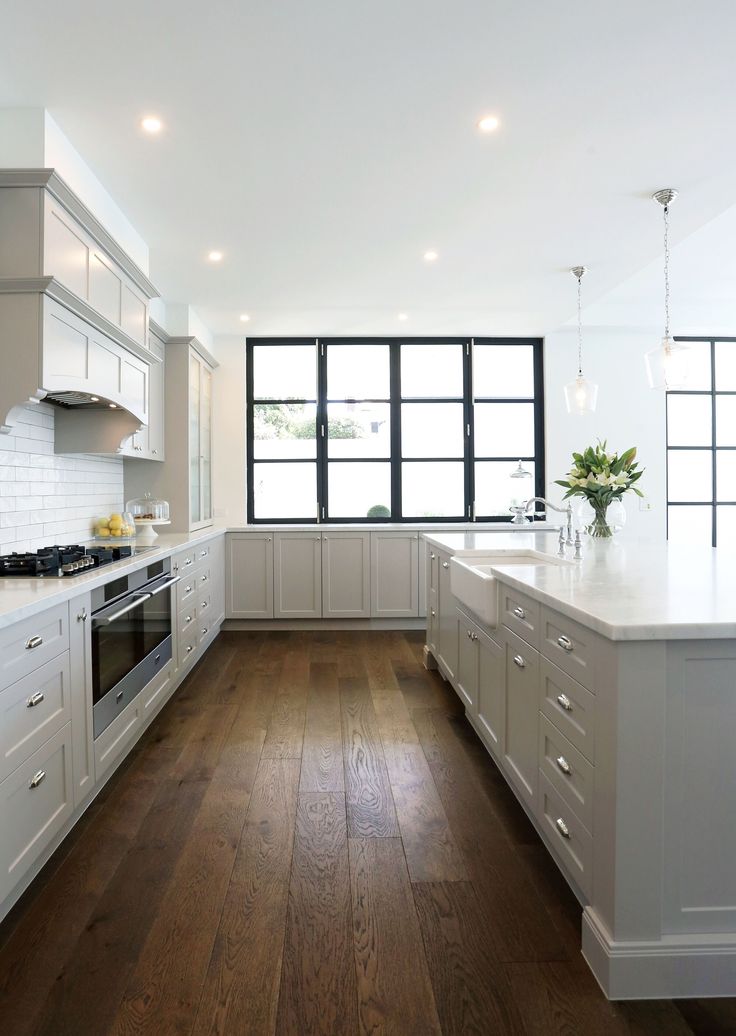 an empty kitchen with white cabinets and wood floors