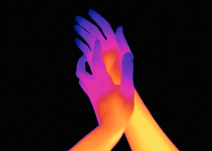 two hands reaching up to each other in the air with neon colors on their arms