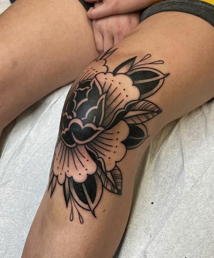 a woman's leg with a black and white flower tattoo on her left thigh