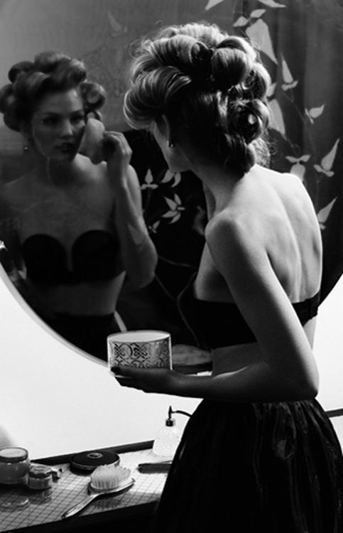 a woman in a black dress is looking at herself in the mirror while brushing her teeth