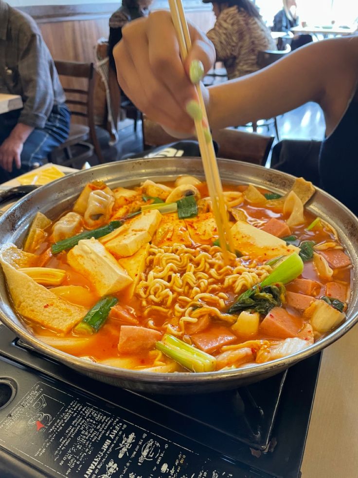 a person is stirring noodles with chopsticks in a pan