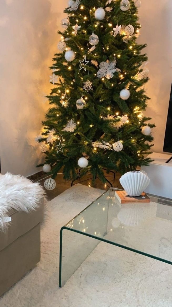 a living room with a christmas tree in the corner and white ornaments on the wall