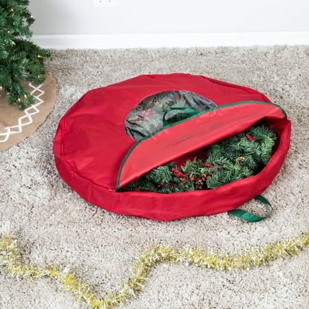 there is a christmas tree in a red bag on the floor next to a small fir tree