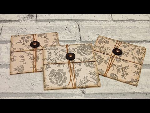 three small envelopes with brown bows on them sitting next to a white brick wall