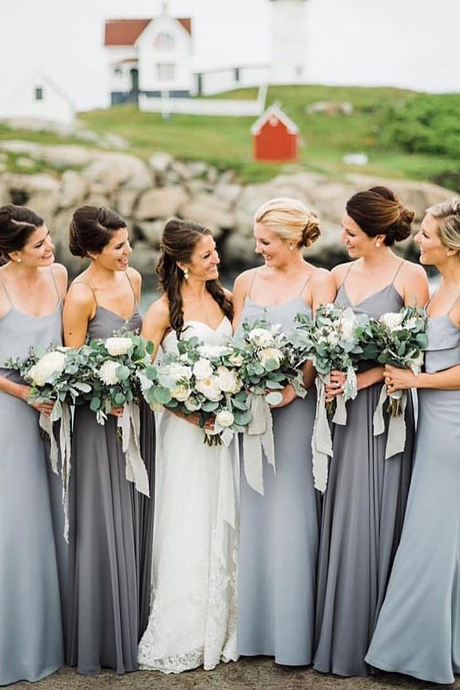 a group of women standing next to each other wearing dresses and holding bouquets in their hands