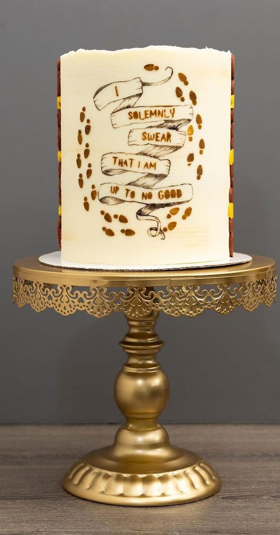 there is a white cake with gold decorations on the top and bottom, sitting on a golden stand