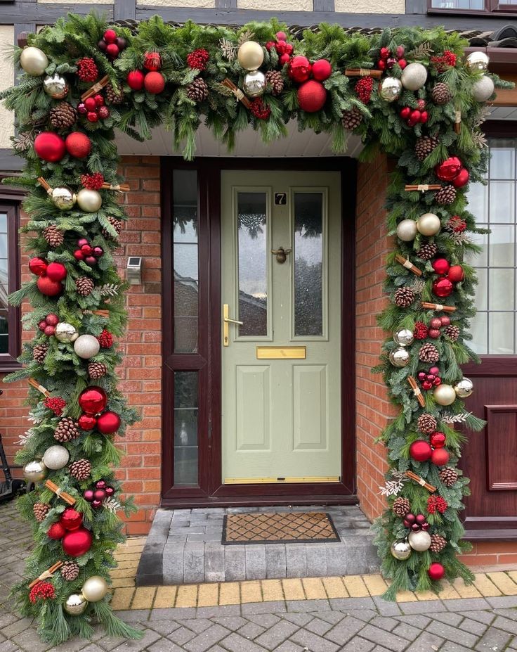 a house decorated for christmas with greenery and ornaments on the front door, along with wreaths