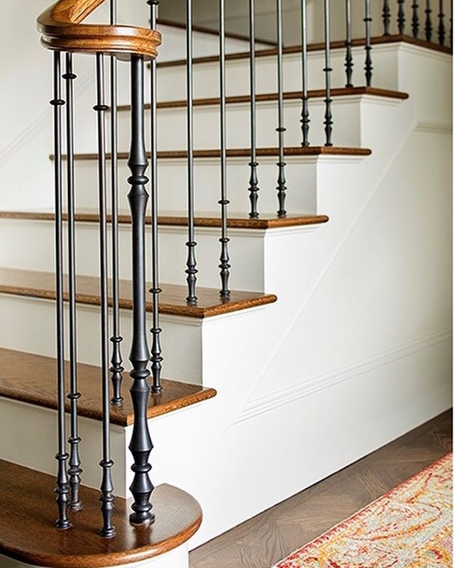 a wooden and metal stair case next to a rug