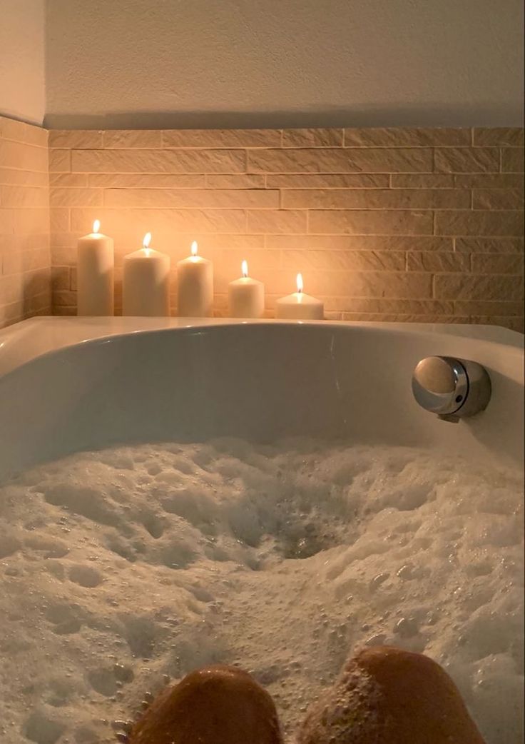 a person's feet in a bathtub with candles