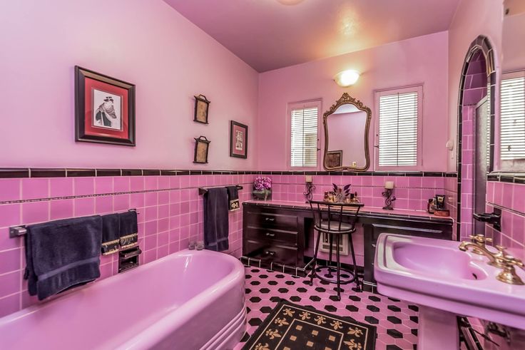 a bathroom with pink and black tile, sink, mirror, and bathtub in it