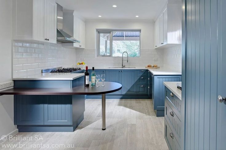 a kitchen with blue cabinets and white counter tops, along with a wine bottle on the table