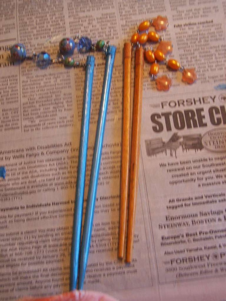 three pencils are laying on top of a newspaper with beaded charms and beads