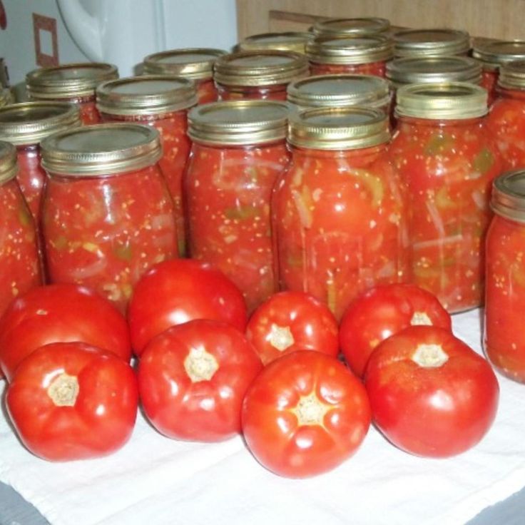 many tomatoes are in jars on a table