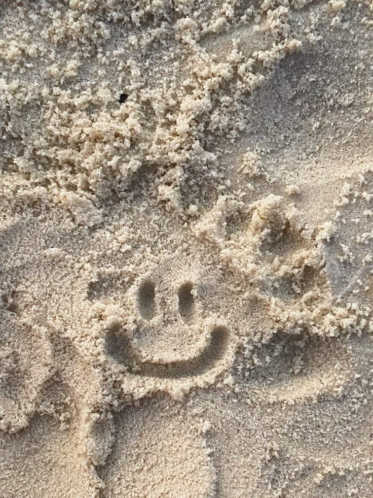 a smiley face drawn in the sand on a beach