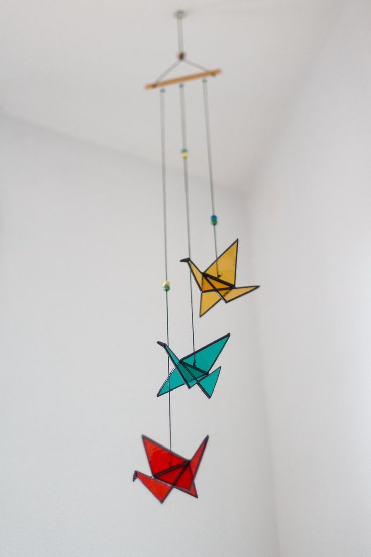 an origami bird mobile hanging from the ceiling in a room with white walls