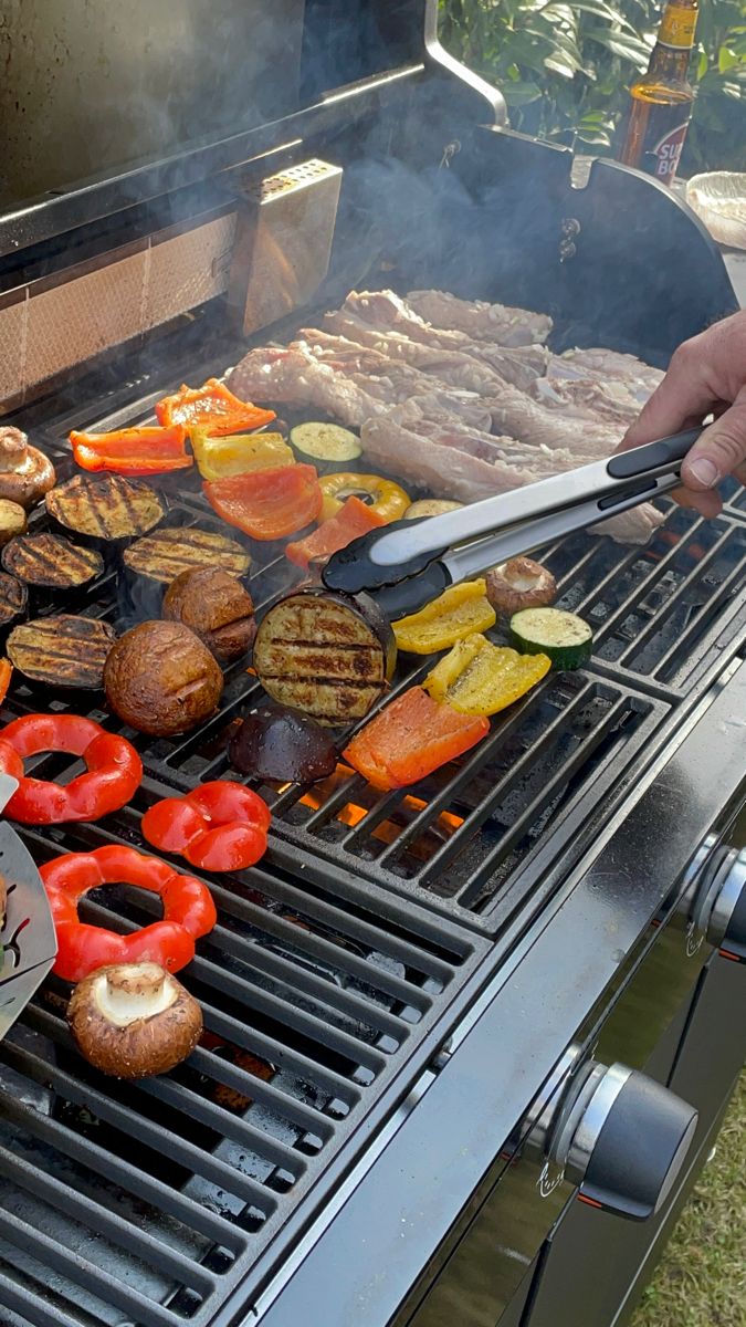 someone is cooking food on the grill with hot dogs and hamburgers in front of them