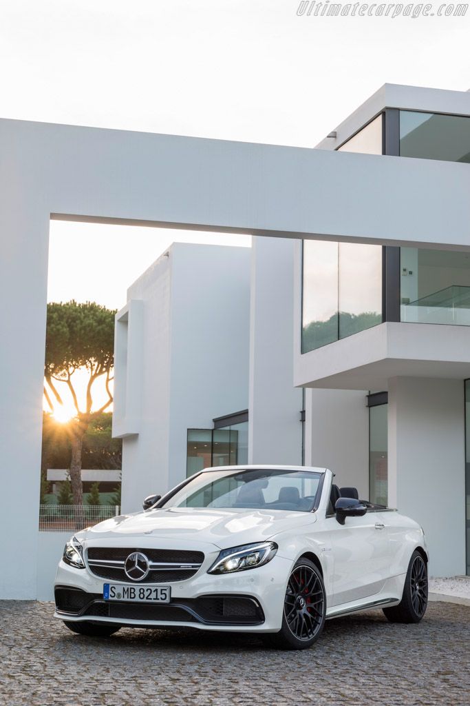 a white car is parked in front of a large modern house with an open driveway