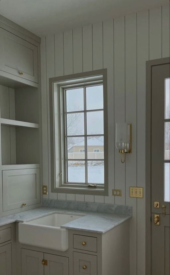 an empty kitchen with white cabinets and marble counter tops in front of a window that looks out onto the water