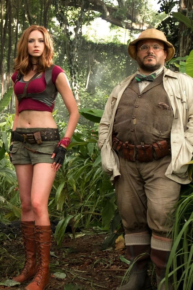 a man and woman standing in the jungle with one wearing an outfit that is made to look like indiana jones