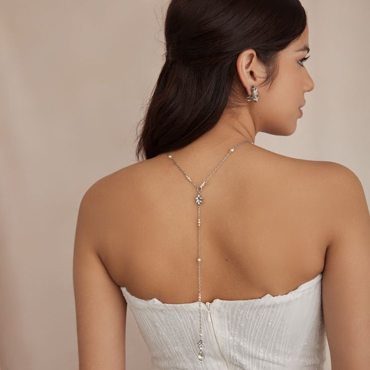 Dive into elegance with our Evangeline necklace, a delicate silver-tone metal chain necklace with dainty Czech glass pearls. This versatile necklace also creates the perfect drop design in back, accentuating your gown from all sides. All Ben-Amun jewelry is handcrafted and made to order in New York City, so please allow 7-14 business days for production before the ship date. Measurements: 26" L Silver Body Chain With Clavicle Design For Wedding, Elegant Wedding Body Chain With Adjustable Chain, Delicate Adjustable Body Chain For Wedding, Delicate Adjustable Wedding Body Chain, Delicate Wedding Body Chain With Adjustable Chain, Silver Delicate Chain Body Chain For Wedding, Silver Lariat Backdrop Necklace With Pearl Drop, Silver Drop Necklace With Pearl Chain For Party, Silver Pearl Chain Drop Necklace For Party