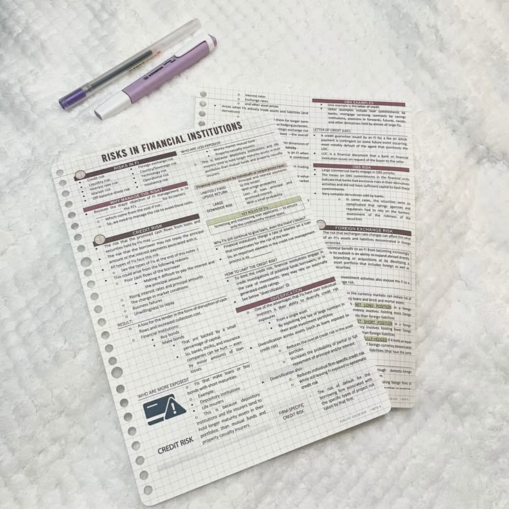 two pieces of paper sitting on top of a bed next to a pen