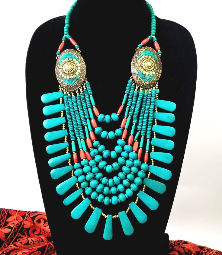 This is a lot of necklace Simulated coral and turquoise bead multi strand statement necklace. Stand out in this striking necklace! 8 full strands of resin beads cascading down from two brass medallions which anchor the strands. First strand starts at 9 inches and last strand is at 14 inches. In a beautiful turquoise/teal blue color of imitation turquoise with gold colored spacer beads. Or bright red coral, or rainbow color. Hook closure. Brass medallions are detailed, with turquoise and coral re Turquoise Multistrand Necklace, Bohemian Turquoise Necklace With Large Beads For Beach, Bohemian Large Beaded Turquoise Necklace For Beach, Bohemian Turquoise Bib Necklace With Colorful Beads, Handmade Turquoise Bohemian Bib Necklace, Bohemian Bib Necklaces With Large Round Beads, Bohemian Turquoise Beads, Handmade Bohemian Multi-strand Turquoise Necklace, Turquoise Multi-strand Bohemian Necklace