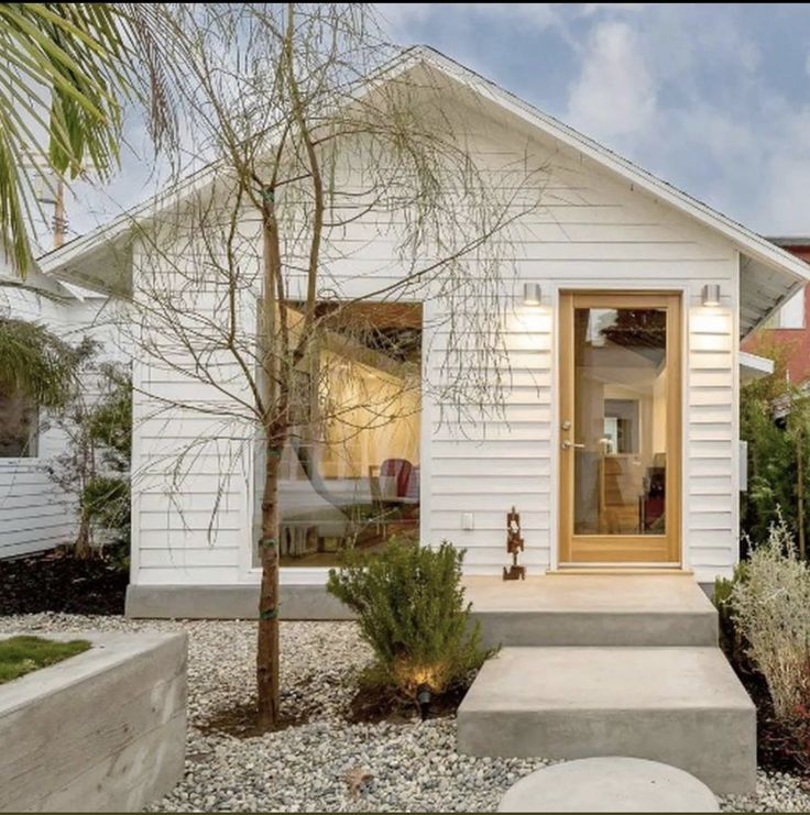 a small white house sitting next to a tree