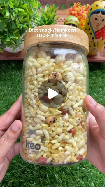 a person holding up a jar full of food in the middle of some green grass