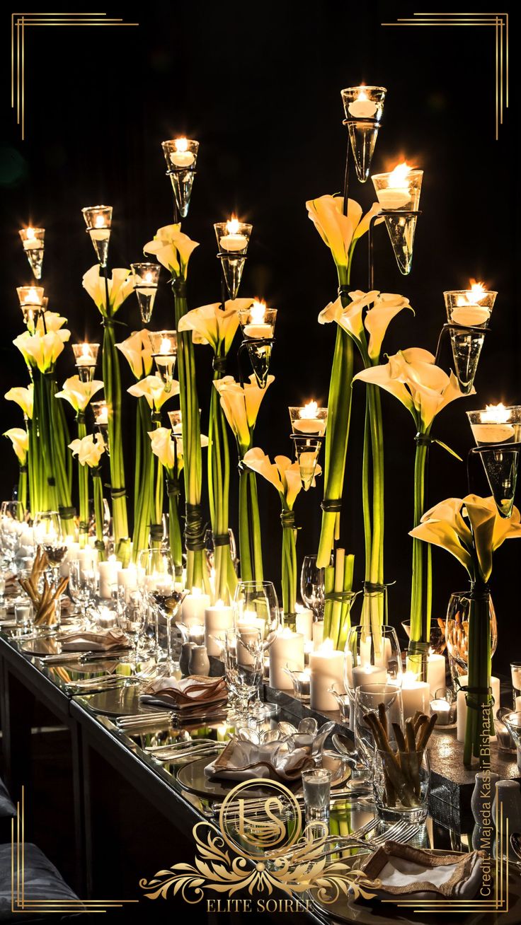 a long table is set with candles and vases filled with flowers, plates and silverware