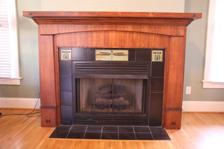 an empty fireplace in a living room with wood flooring and tile on the mantle