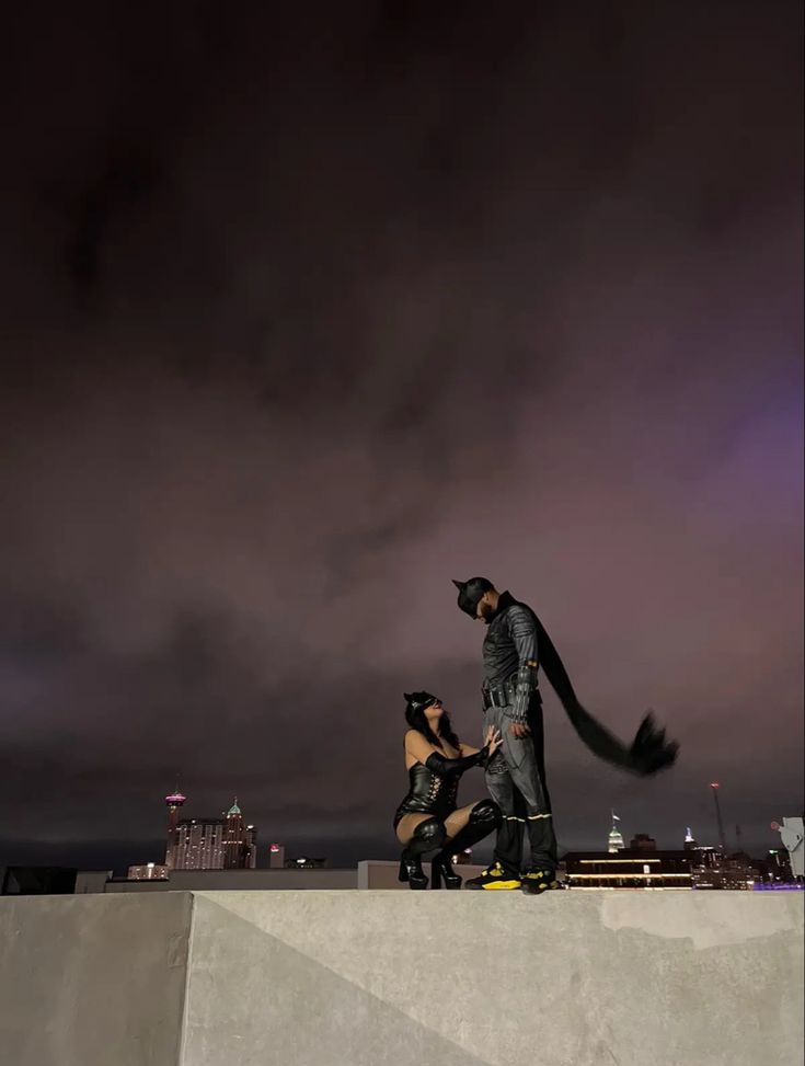 two people standing on top of a cement wall with a cat in the air above them