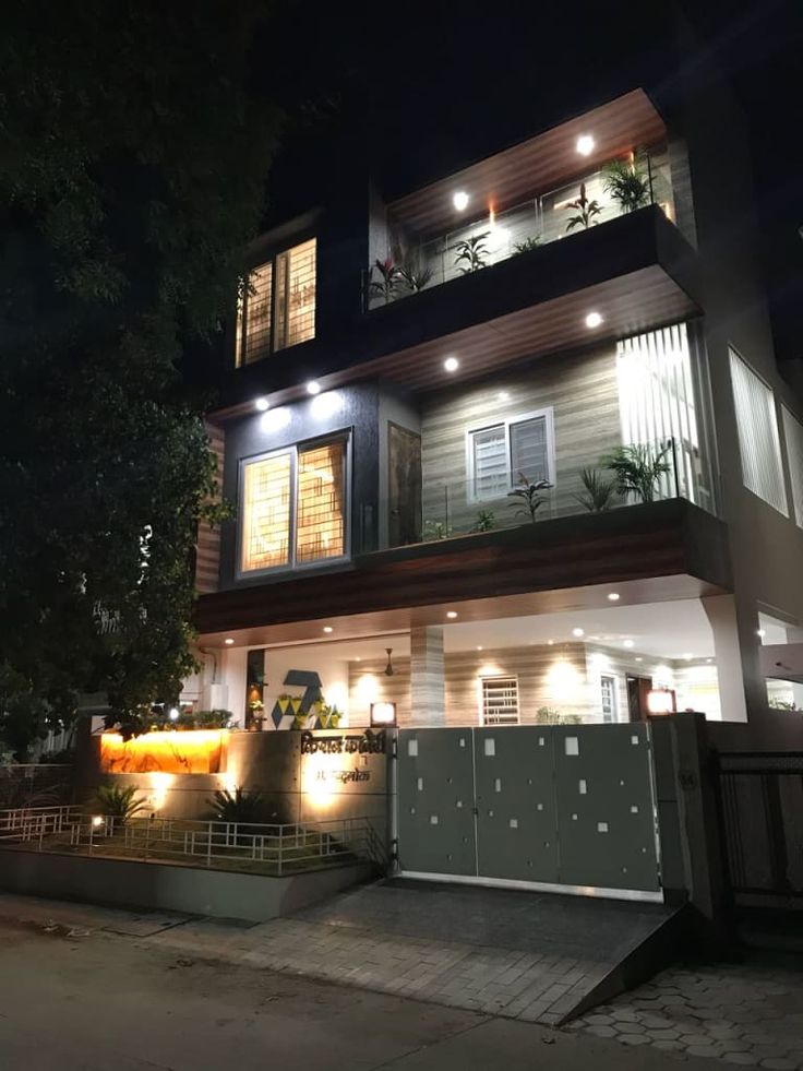 a house that is lit up at night with lights on the windows and balconies