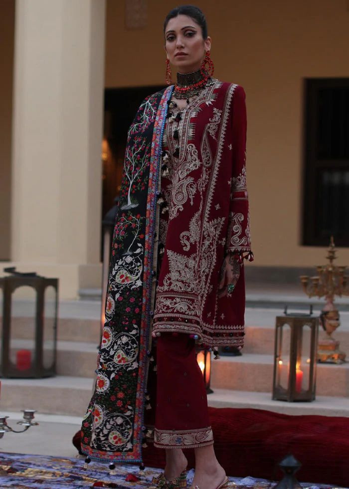 a woman standing in front of a building wearing a red and black outfit with elaborate designs