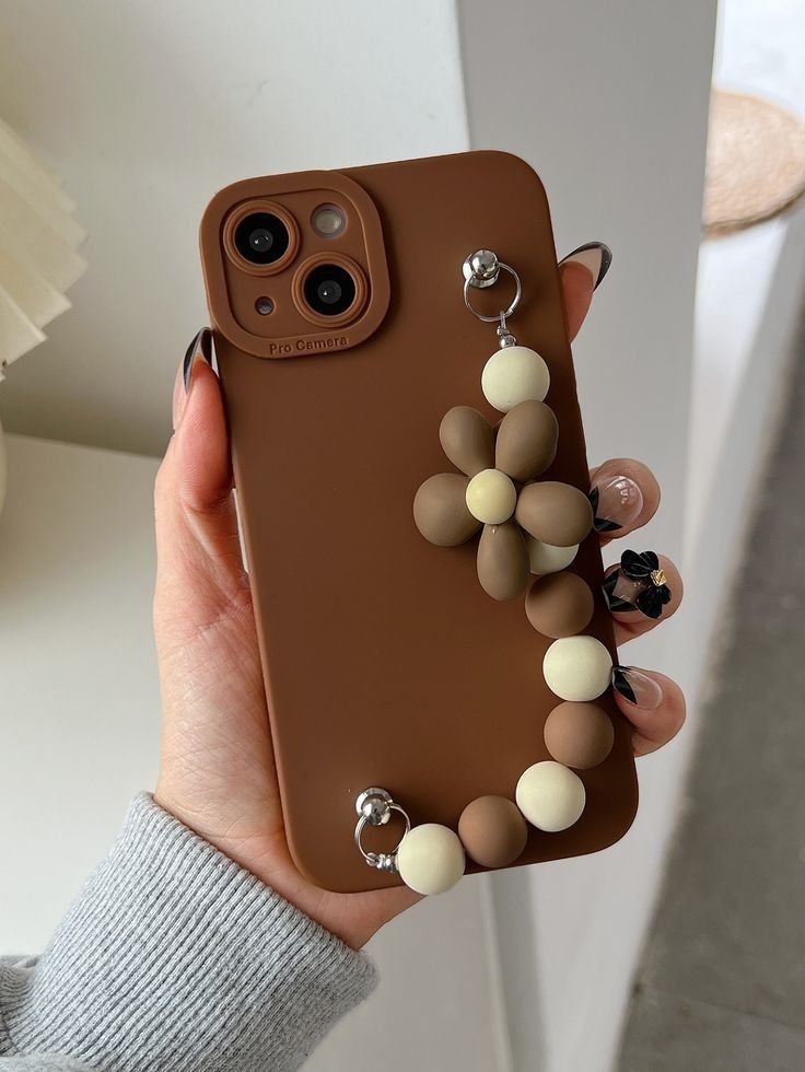 a woman is holding up her phone case with some beads on the front and sides