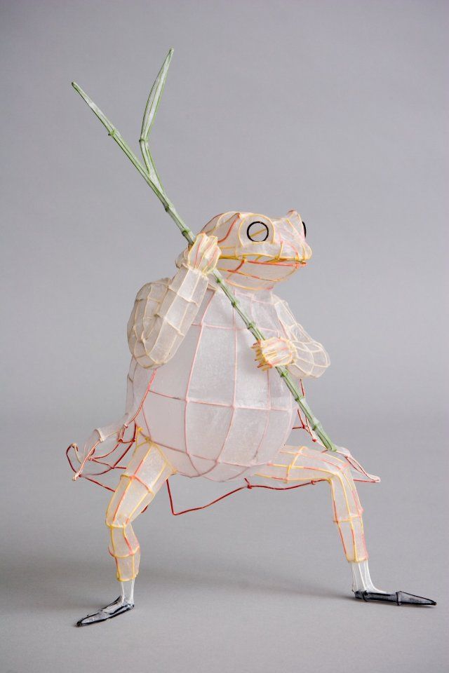 a paper sculpture of a frog holding a plant