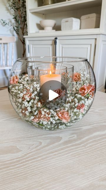 a vase filled with flowers on top of a table next to a lit candle in it