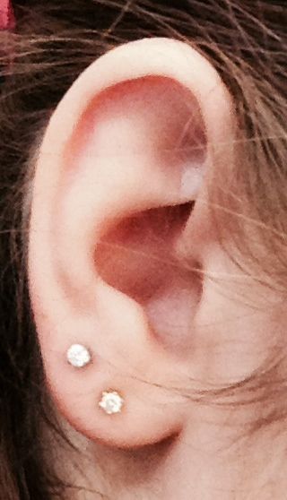 a woman's ear with two small white stones on it