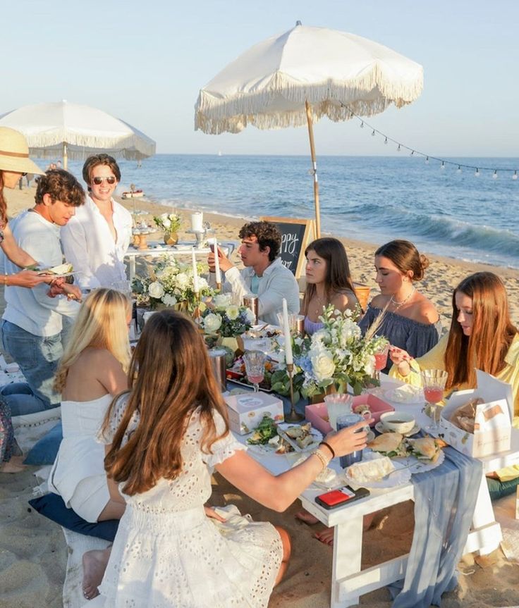 a group of people sitting at a table on the beach