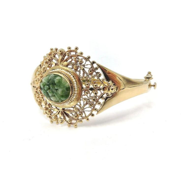 This is part of Chairish’s Fine Jewelry assortment.  This elegant bracelet is made of 14k gold and decorated with a central reticulated piece of green jade. The centre jade piece protrudes about a 1/4 of an inch from the gold setting and is carved with flower patterns. A lovely ring of seed pearls decorates the gold setting around the oval jade stone. From the central jade, as if emitting sinuous line-work, the gold work has a woven lace-like gold organic pattern detailed with beads of gold. The Victorian Green Bracelet Jewelry, Elegant Jade Bangle, Elegant Jade Bracelets For Wedding, Victorian Green Bracelets As Gift, Victorian Green Bracelets For Gifts, Victorian Style Green Bracelets For Gifts, Green Bangle For Formal Occasions, Fine Jewelry Style, Elegant Green Gemstone Gold Bracelet, Elegant Oval Green Bangle