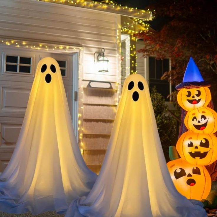 three lighted pumpkins in front of a house with ghost faces on them and lights around