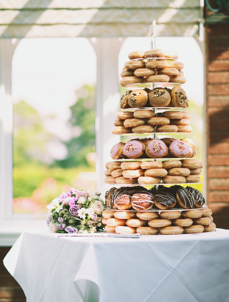 a tower of doughnuts sitting on top of a table next to a window