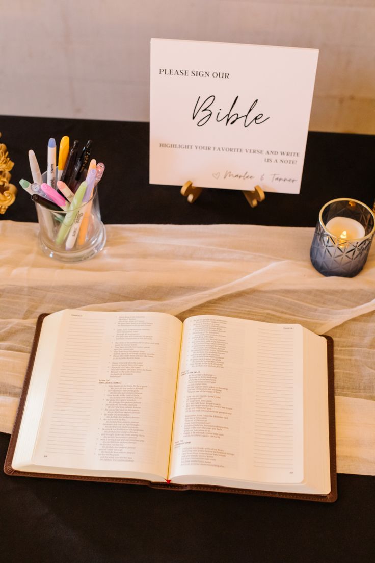 an open book sitting on top of a table next to a vase filled with flowers